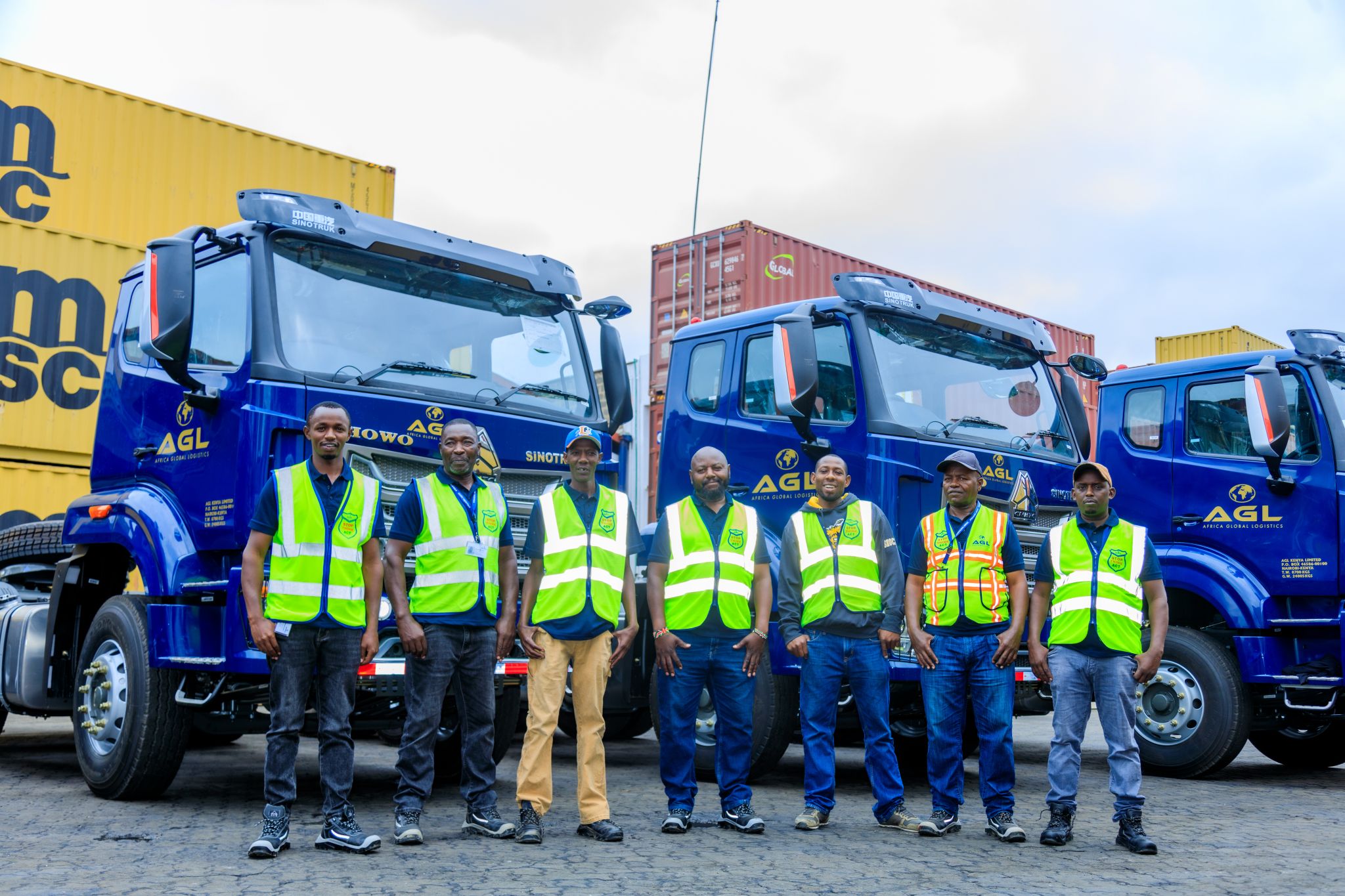 AGL Kenya team standing in front of Sinotruk trucks